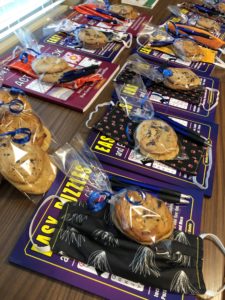 A close-up of puzzles, masks, a bag of cookies tied with a blue ribbon, and two pens