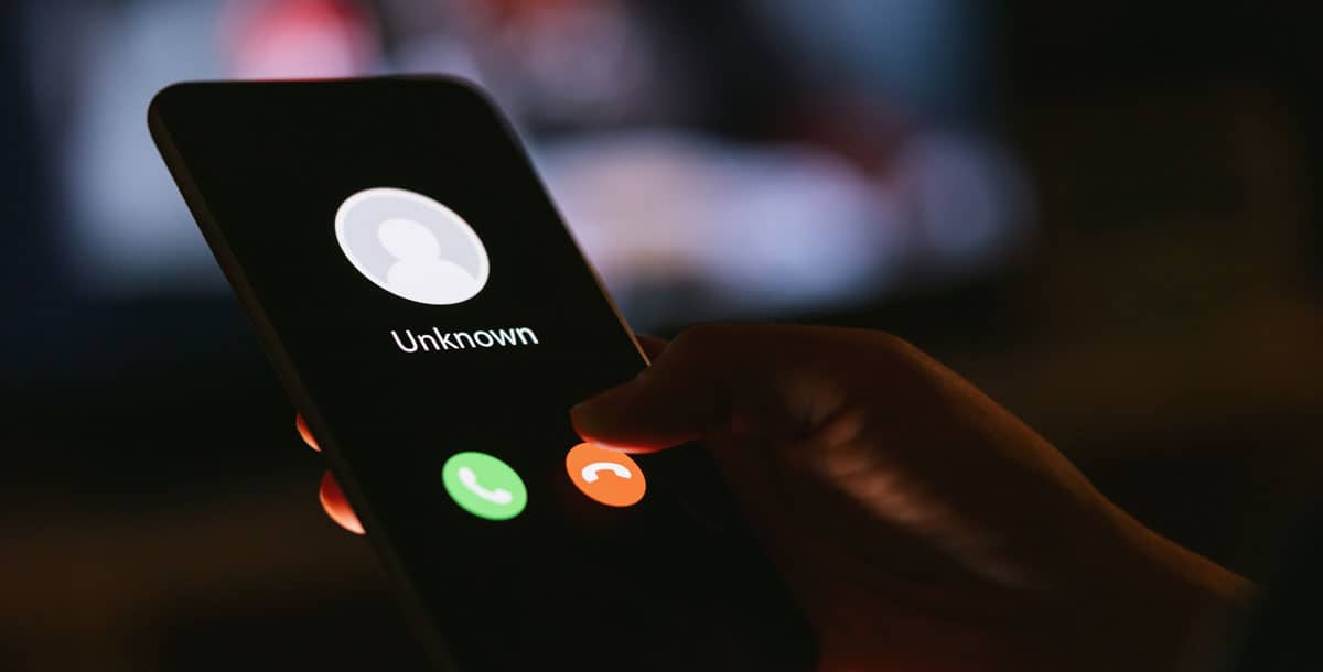 A close-up of an iPhone with an illustration of a call from an Unknown person.