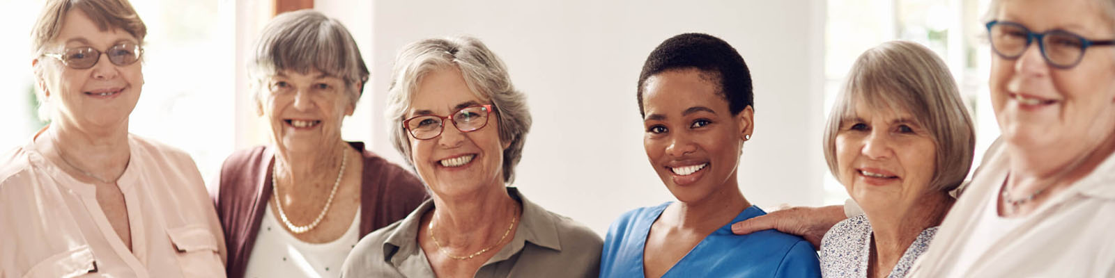 A group of six women smiling with a caregiver in the middle.