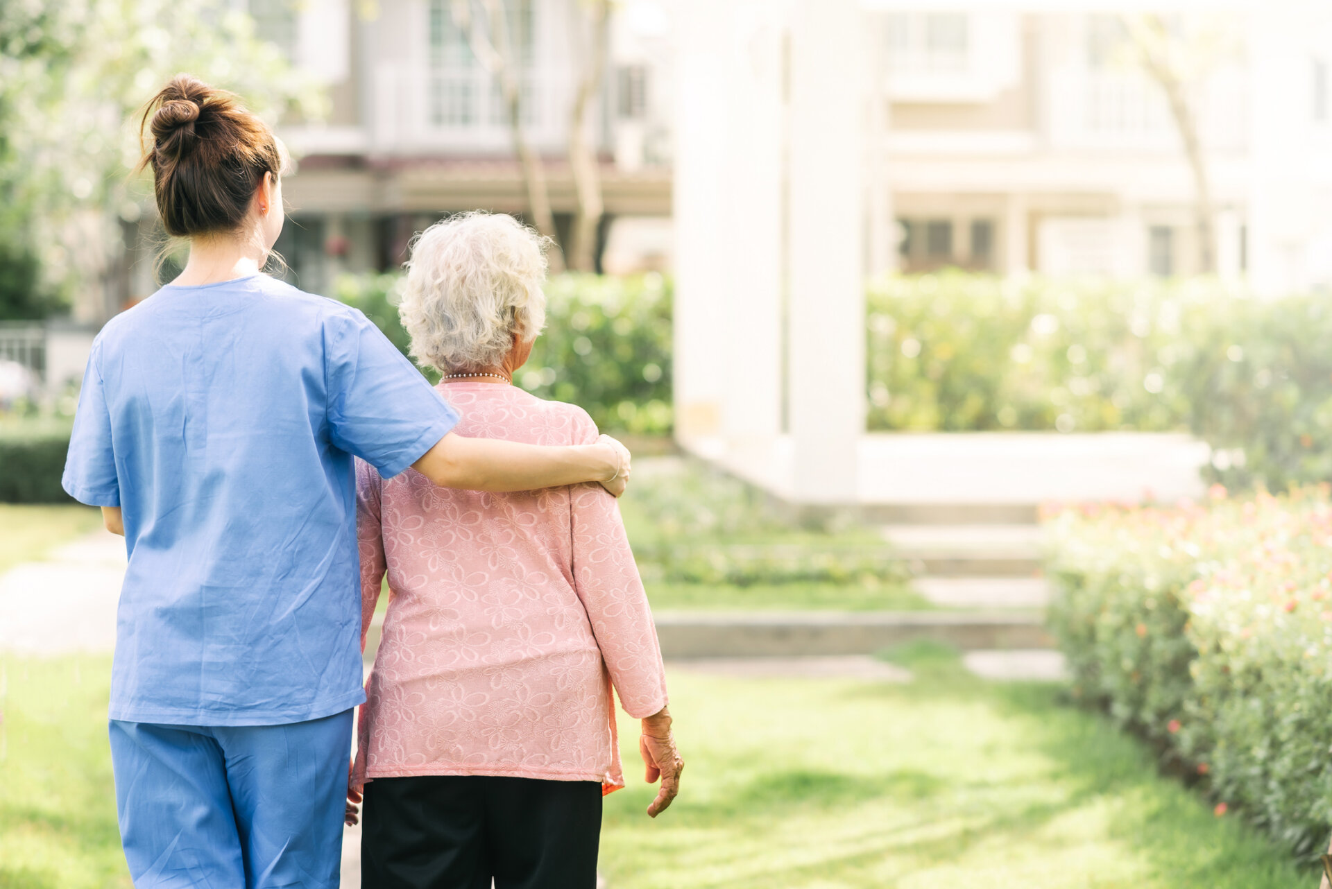 A senior living employee walking with a female resident outdoors