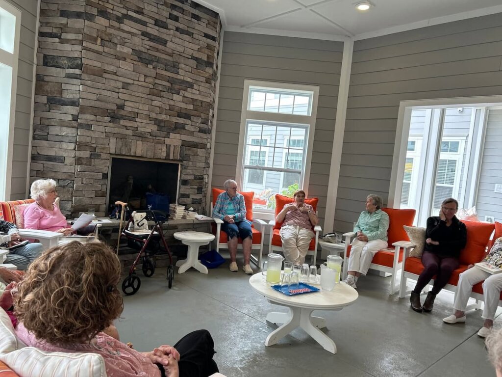 Traditions at Camargo residents sitting in a circle having a discussion during book club with lemonade on a table in the center